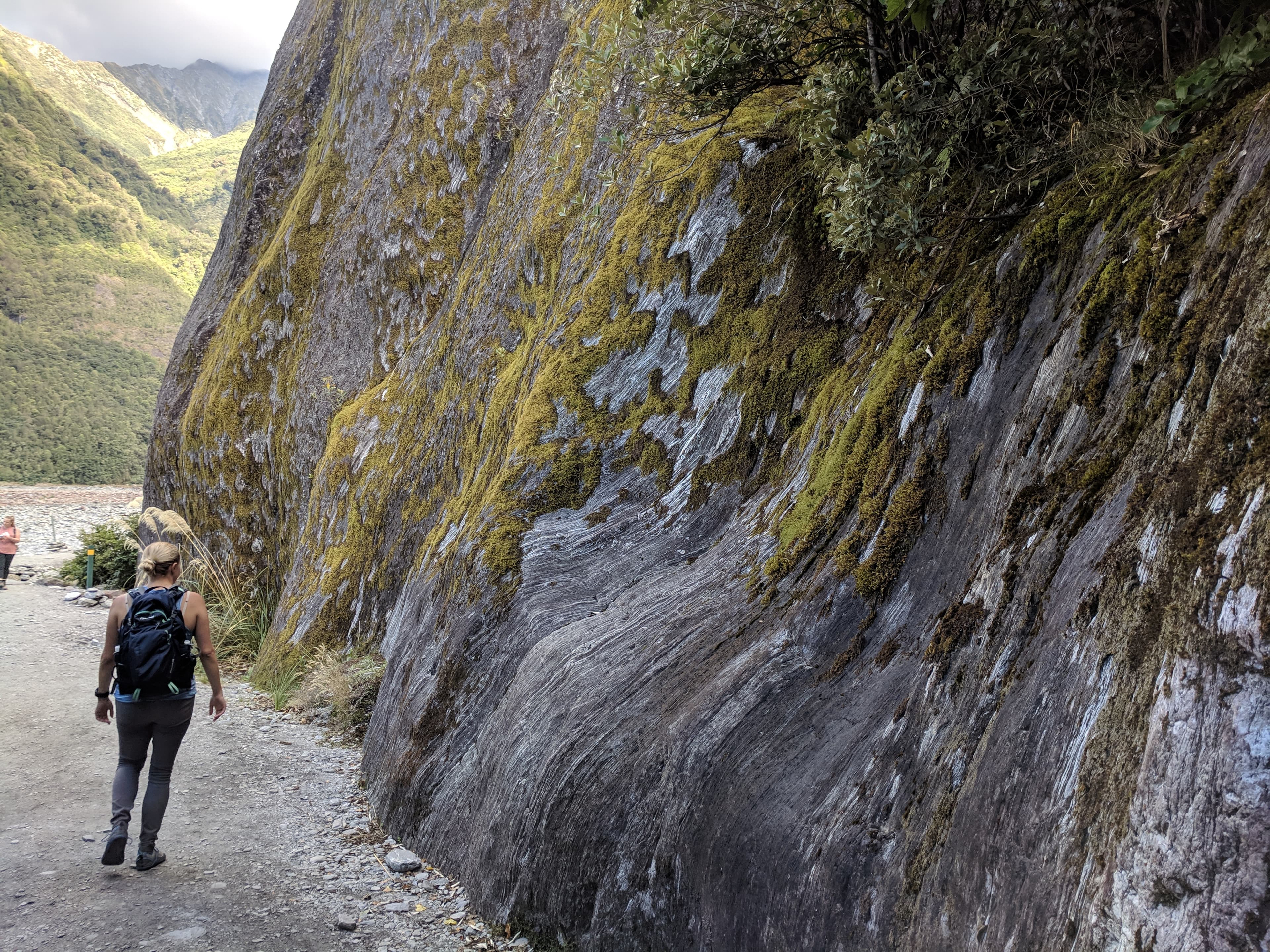 Lauren walking past a cool wall going to Franz Josef Glacier